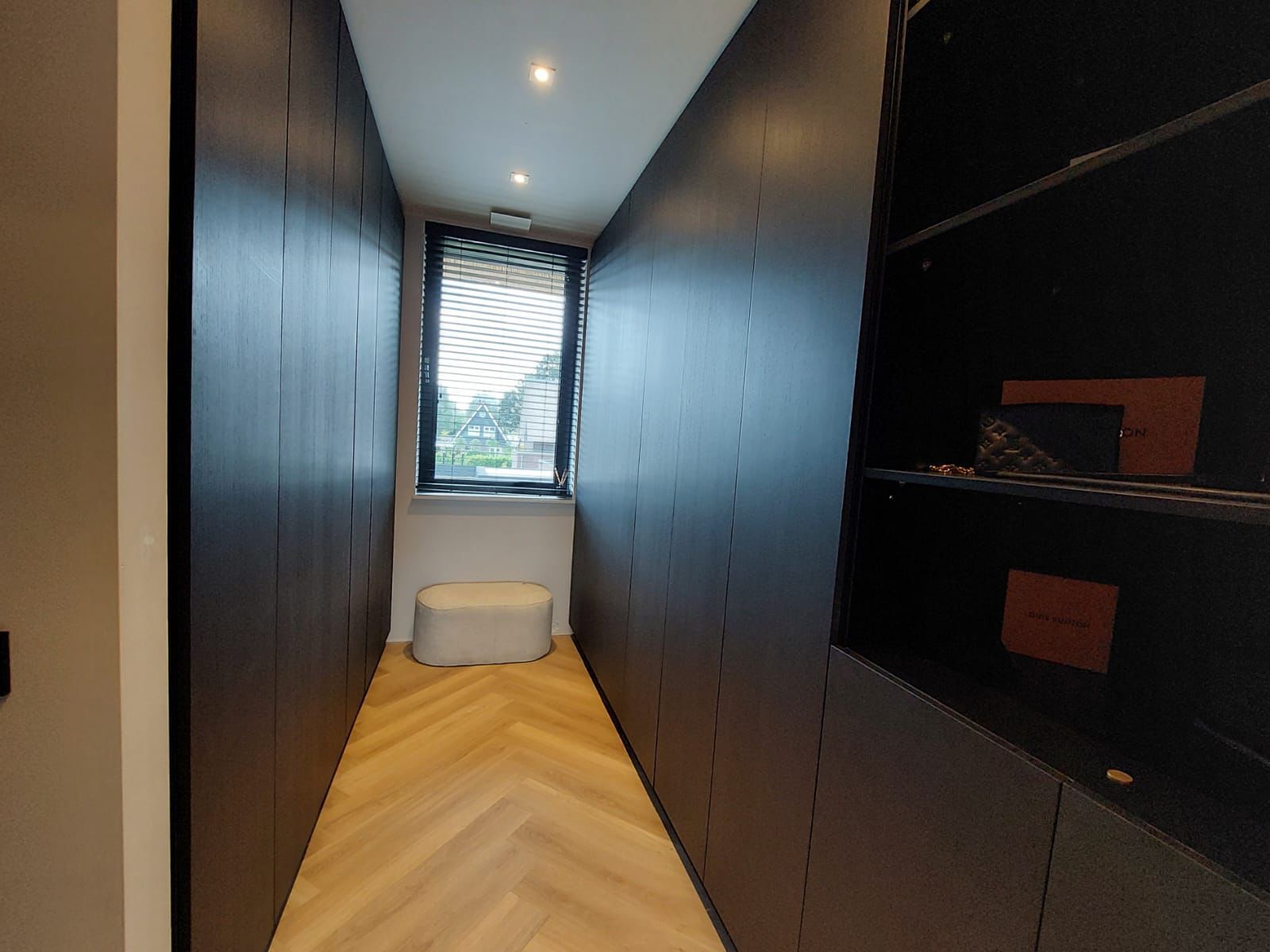 a long hallway with a window and a stool