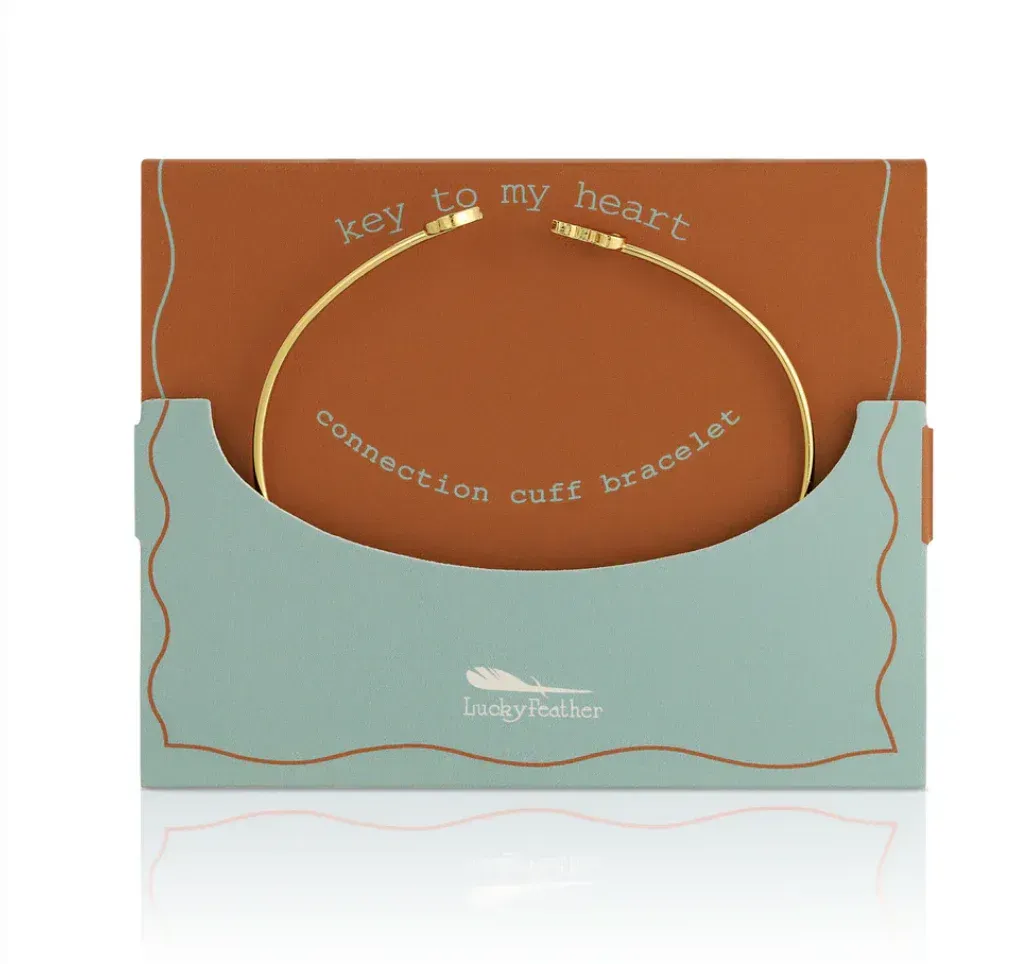 Gold cuff bracelet on a gift card, brown and teal. 