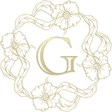 Gold letter "G" encircled by a floral and ribbon wreath.