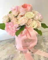 Pink and cream roses in a pink box tied with a matching ribbon.
