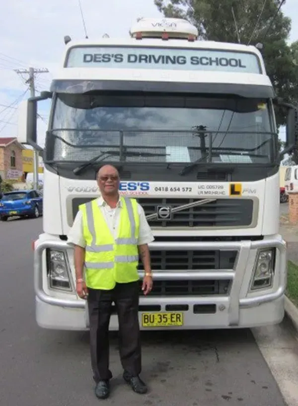 Man in safety vest stands in front of a white truck for