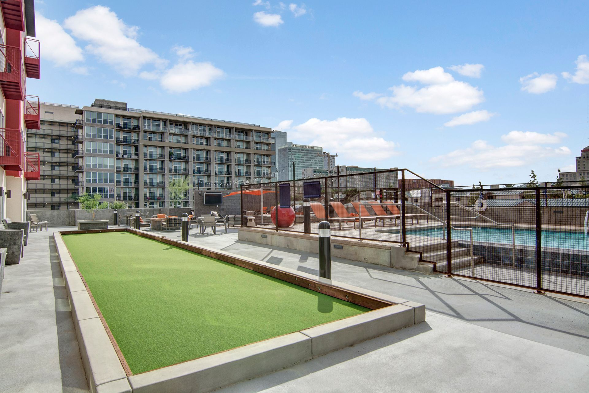 There is a pool in the background and a shuffleboard court in the foreground.