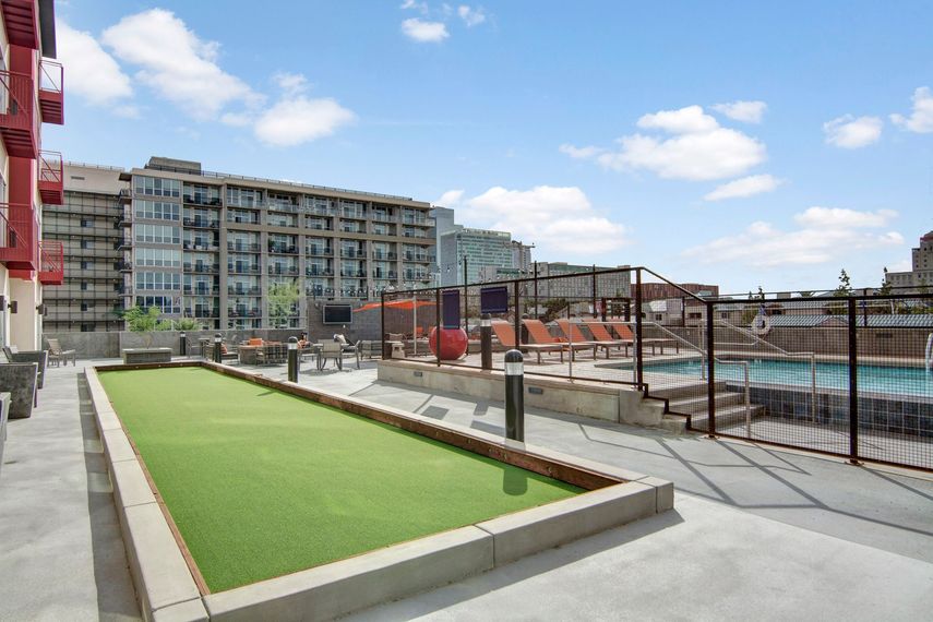 There is a pool in the background and a shuffleboard court in the foreground.