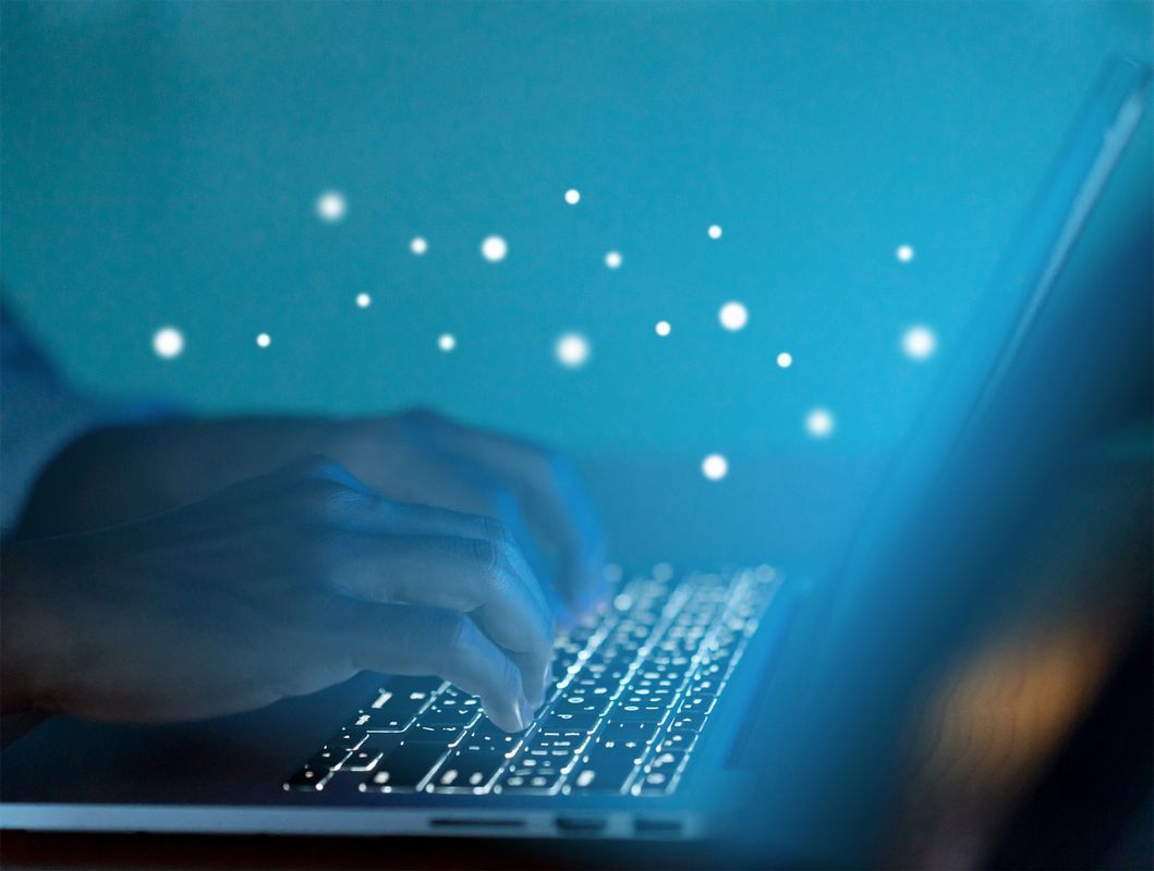 Hands typing on a laptop keyboard emitting blue light. White glowing dots emanate upwards.