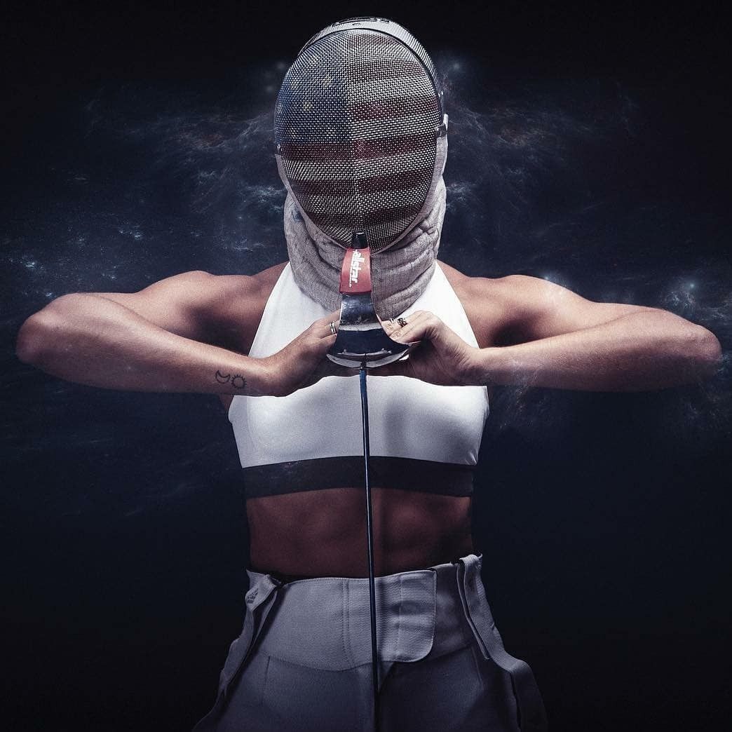 Fencer in white uniform, hands on weapon, facing forward, in front of a dark, swirling background.