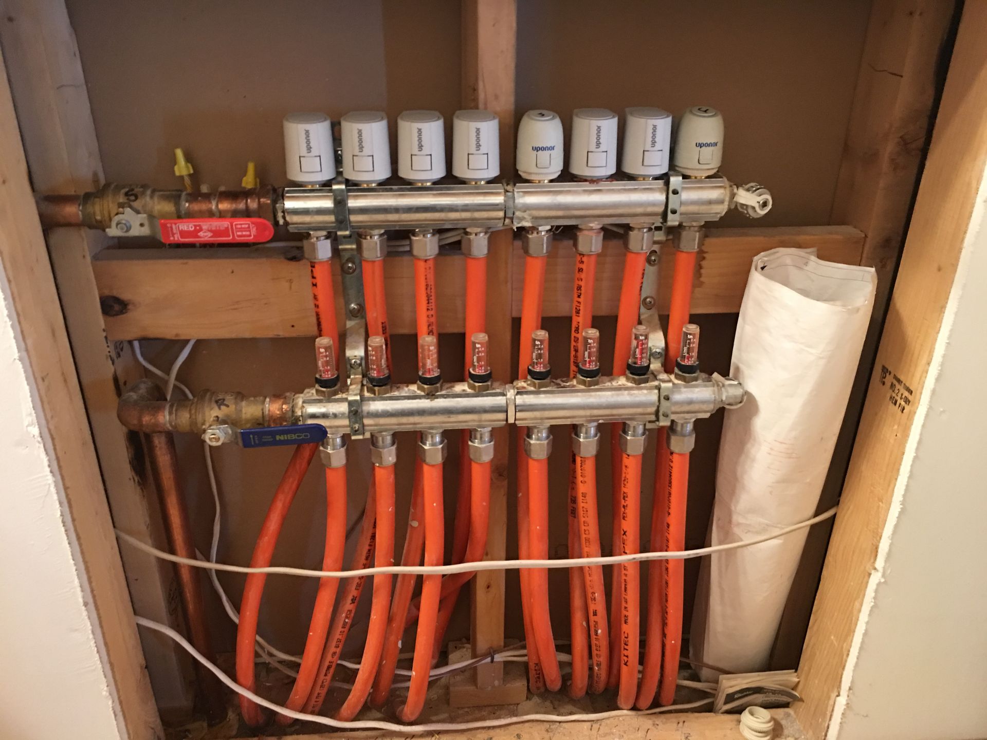 A bunch of orange pipes are connected to a heater.