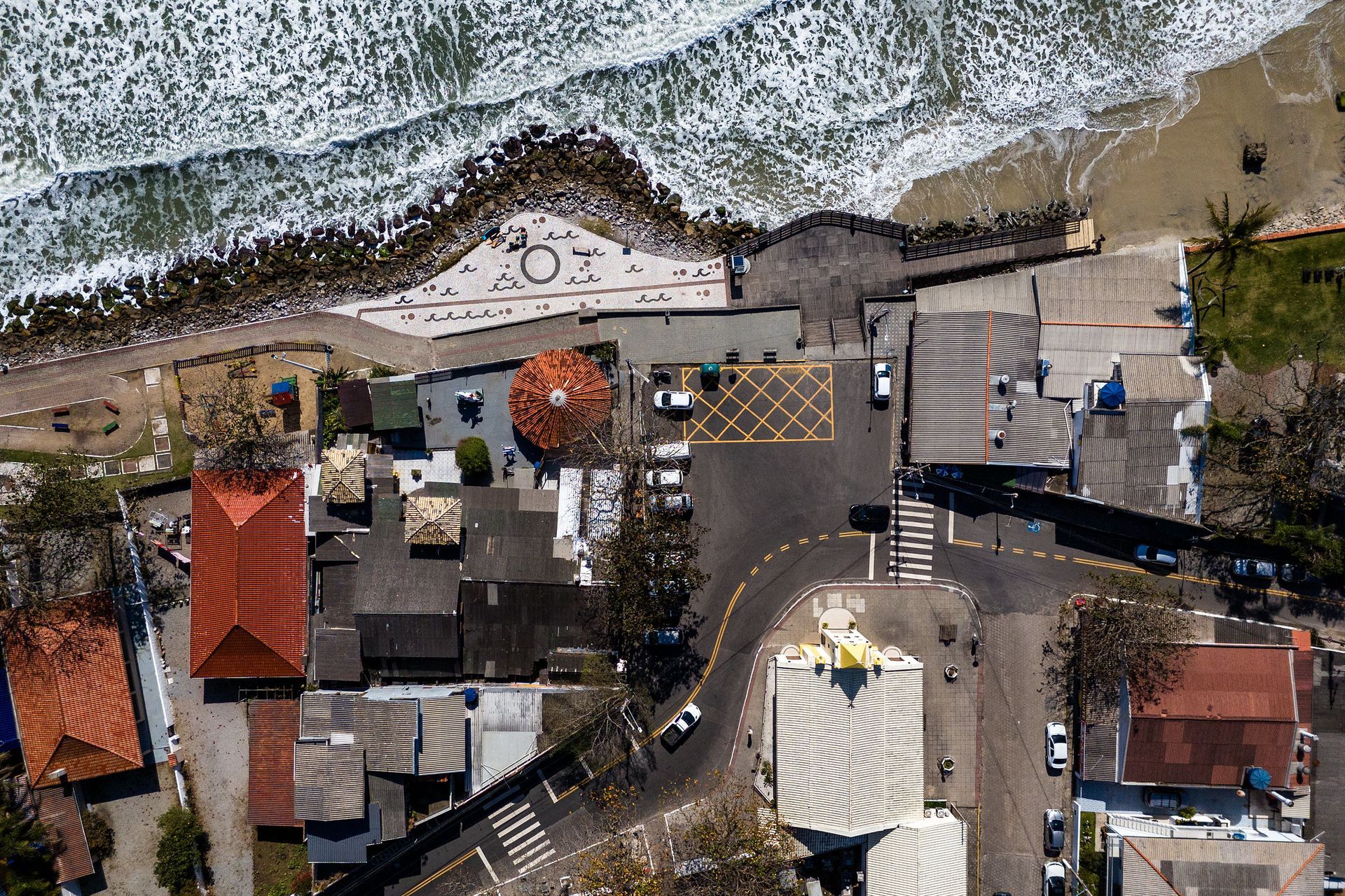 Vista aérea de uma cidade costeira com edifícios, uma praia e o oceano.
