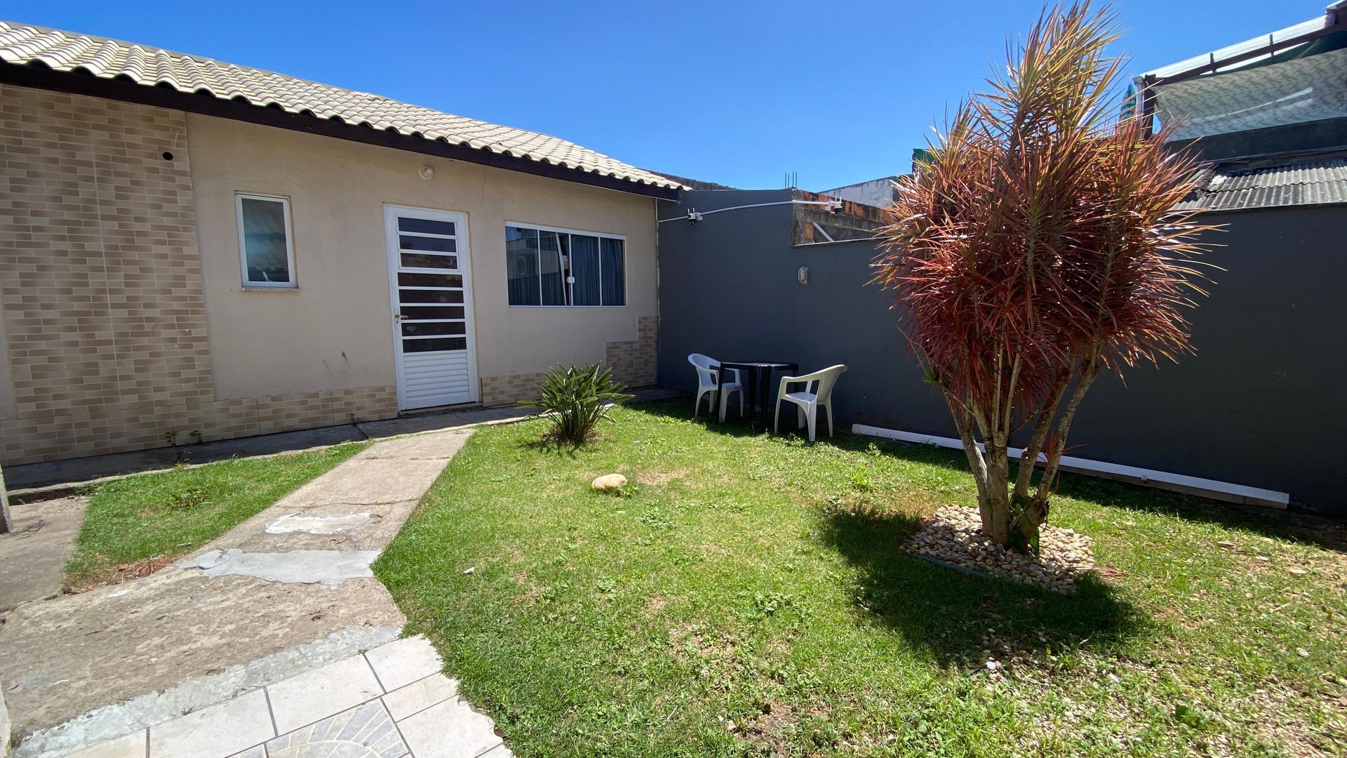 Uma pequena casa com gramado e pátio em um dia ensolarado.