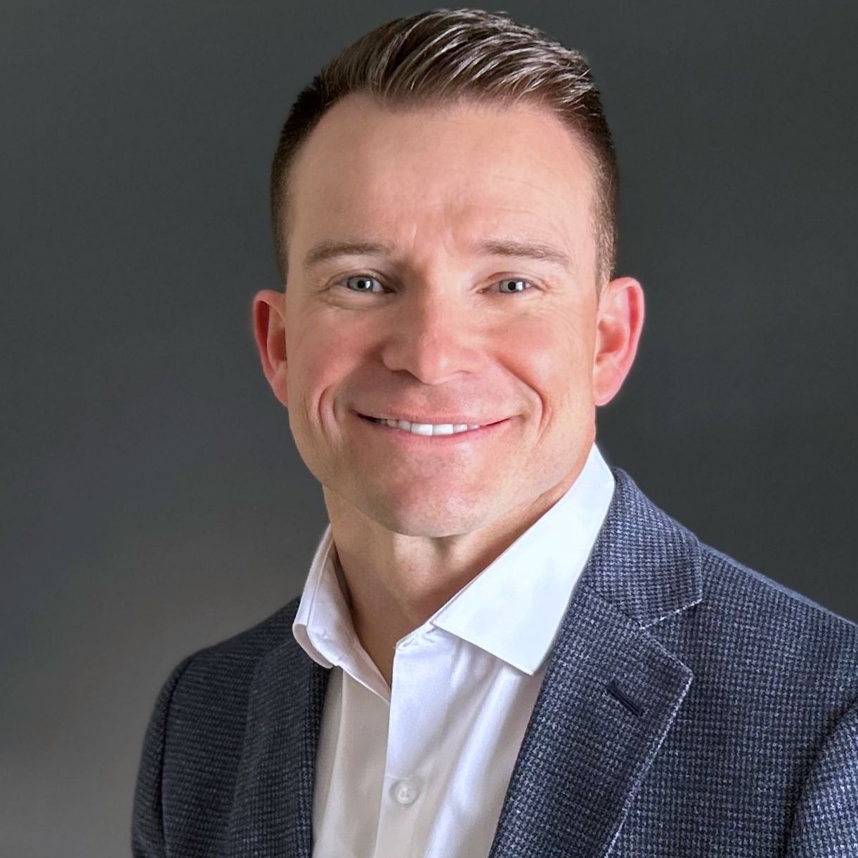 A man in a suit and white shirt is smiling for the camera.