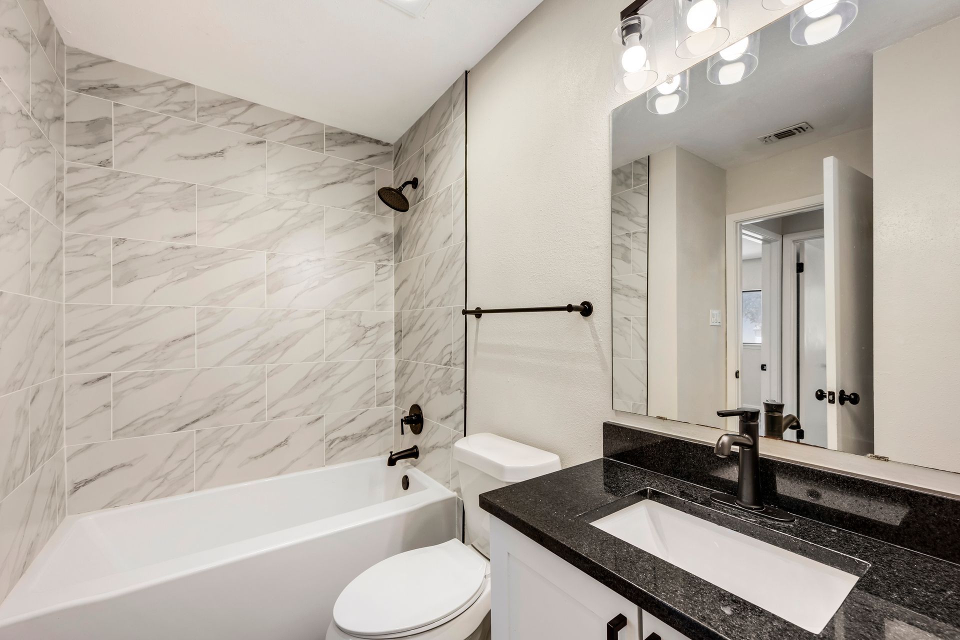 A bathroom with a sink , toilet , bathtub and mirror.