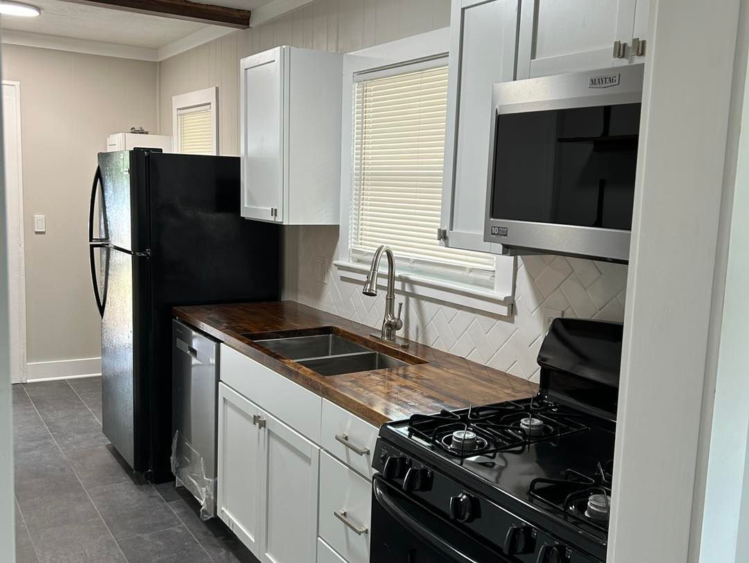 A kitchen with a refrigerator , stove , sink and microwave.