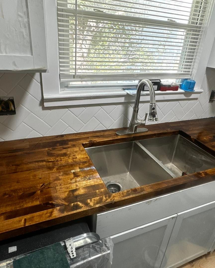 A kitchen with a stainless steel sink and a wooden counter top.
