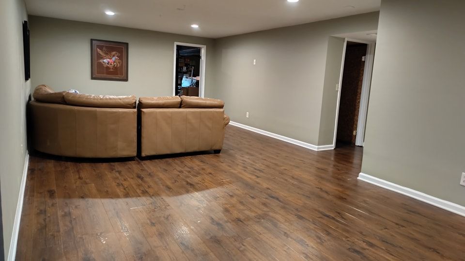 An empty basement with hardwood floors and a couch.