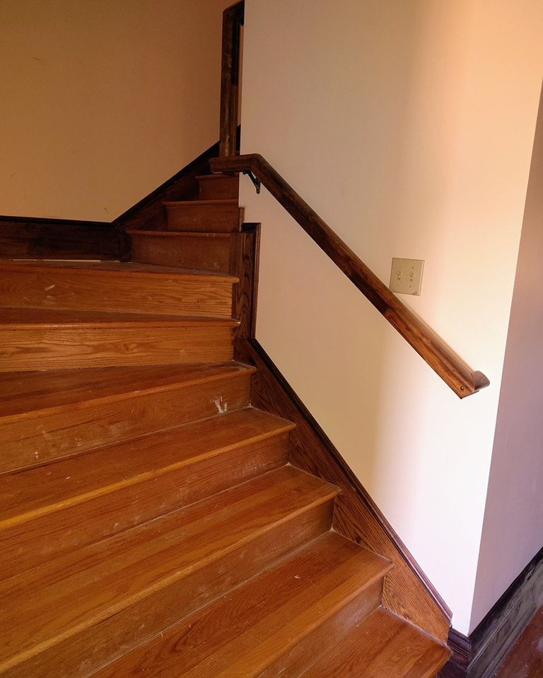 A wooden staircase with a white wall and a wooden railing