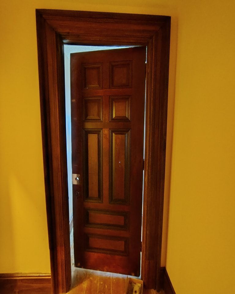 A wooden door is open in a room with yellow walls