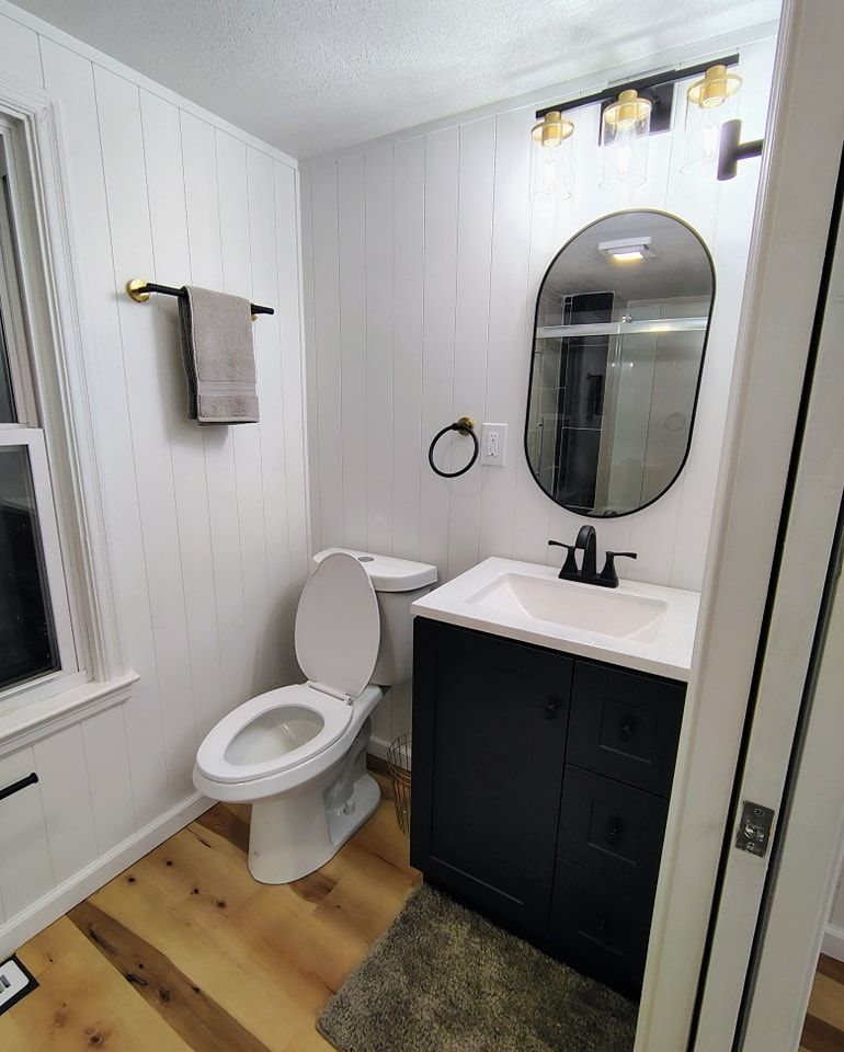 A bathroom with a toilet , sink and mirror.