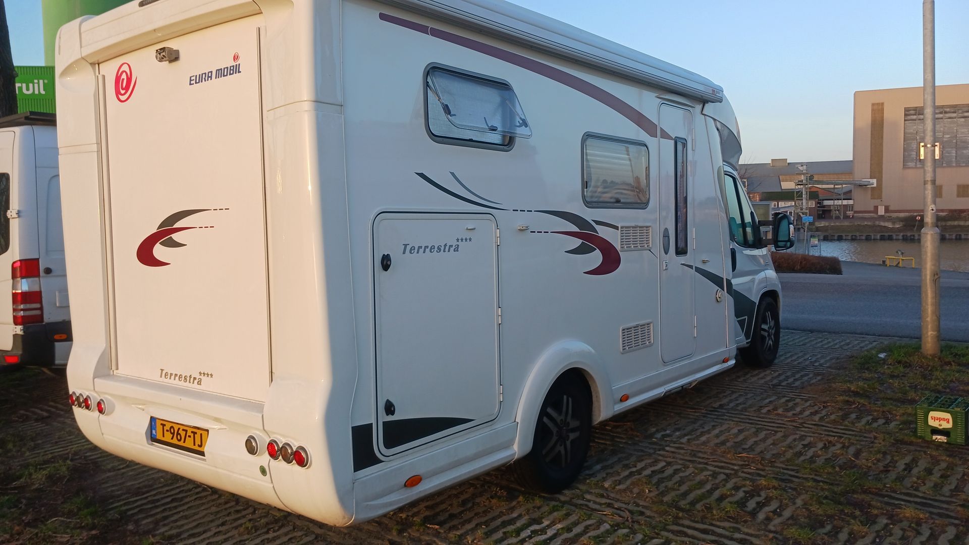 Een witte camper staat geparkeerd op een parkeerplaats.