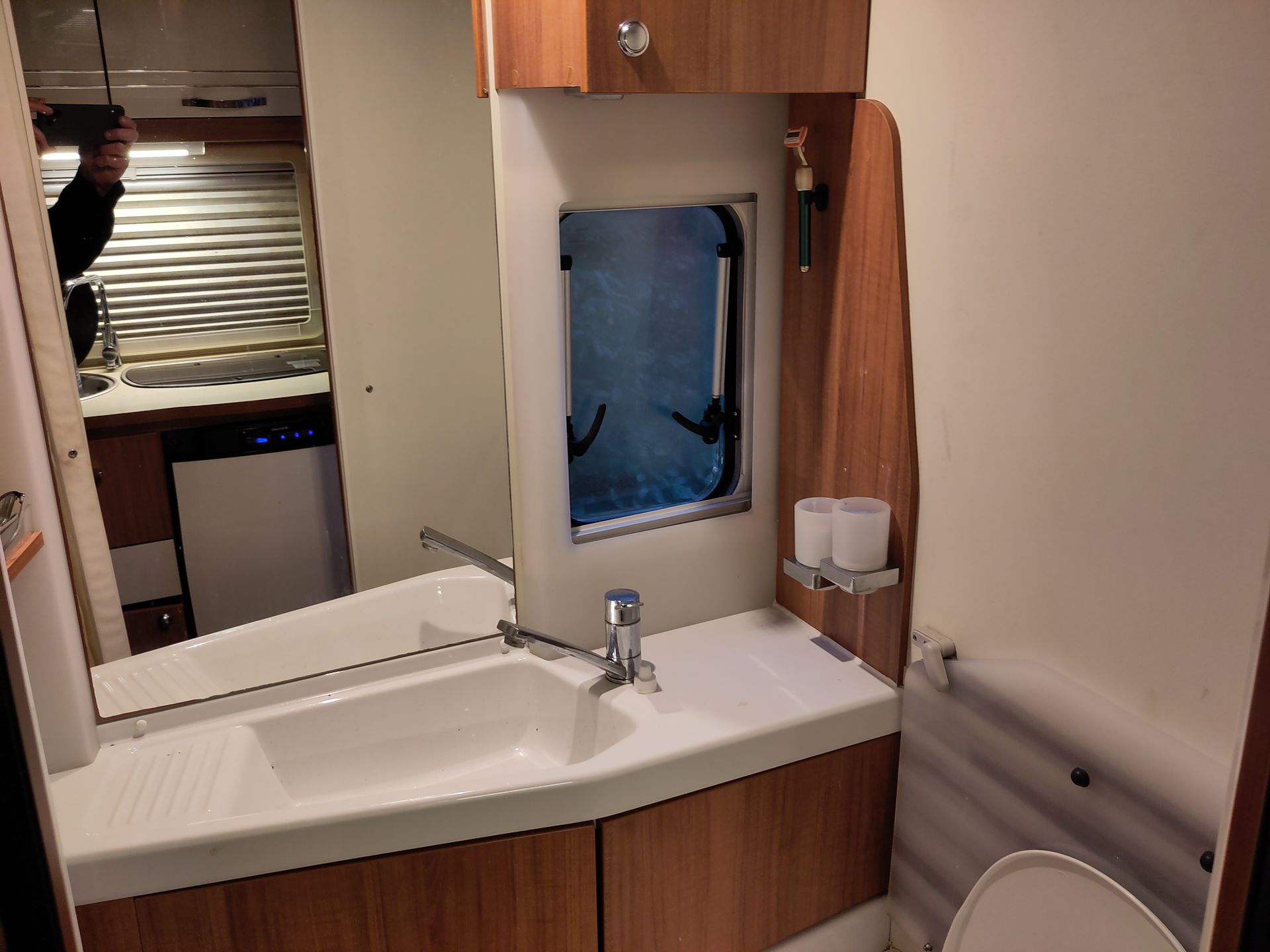 Een luxe badkamer met wastafel, toilet en spiegel on camper.