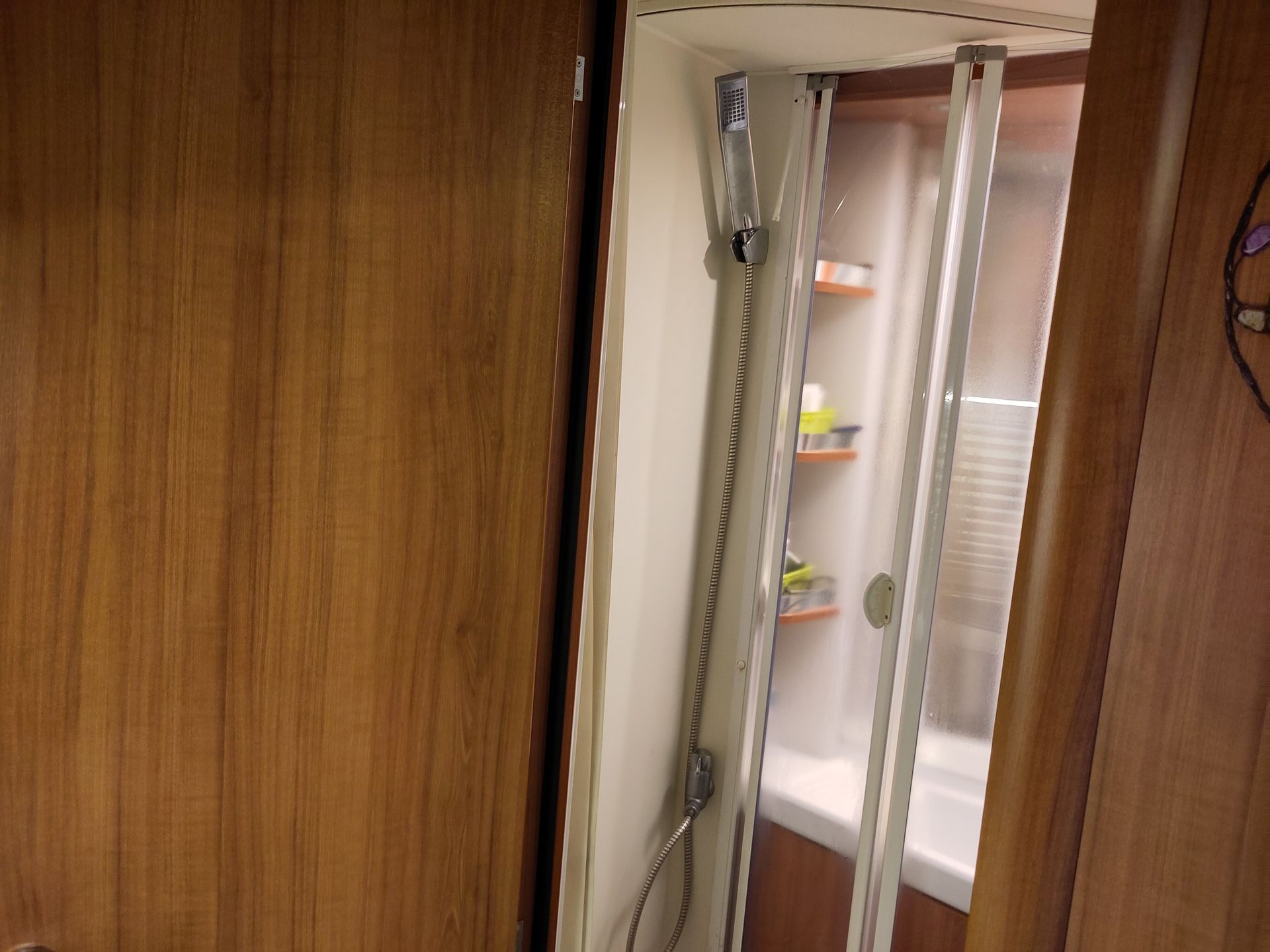 Een fijne badkamer met een douchecabine en een spiegel in camper.