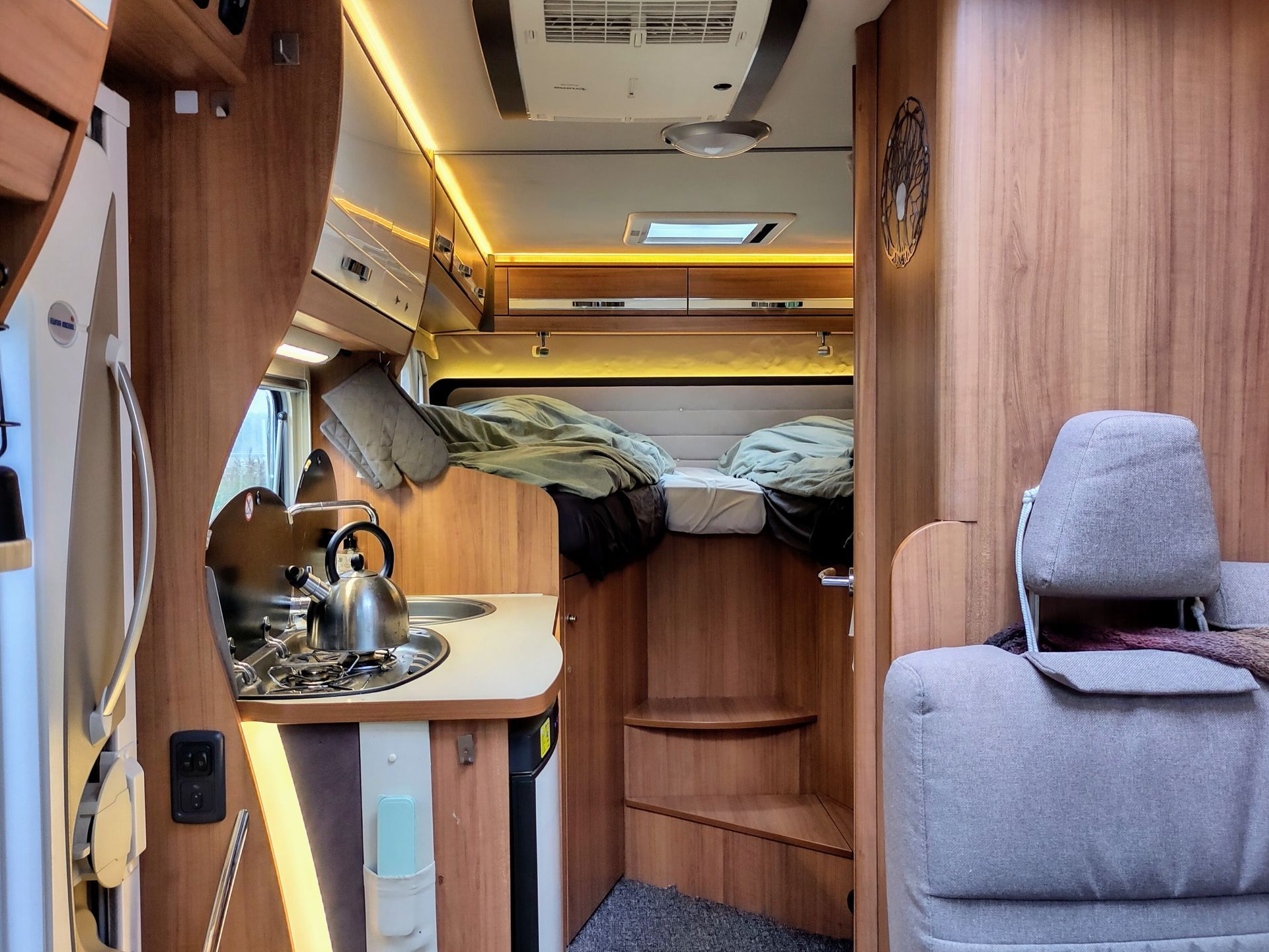 De binnenkant van een camper met een bed en een keuken.
