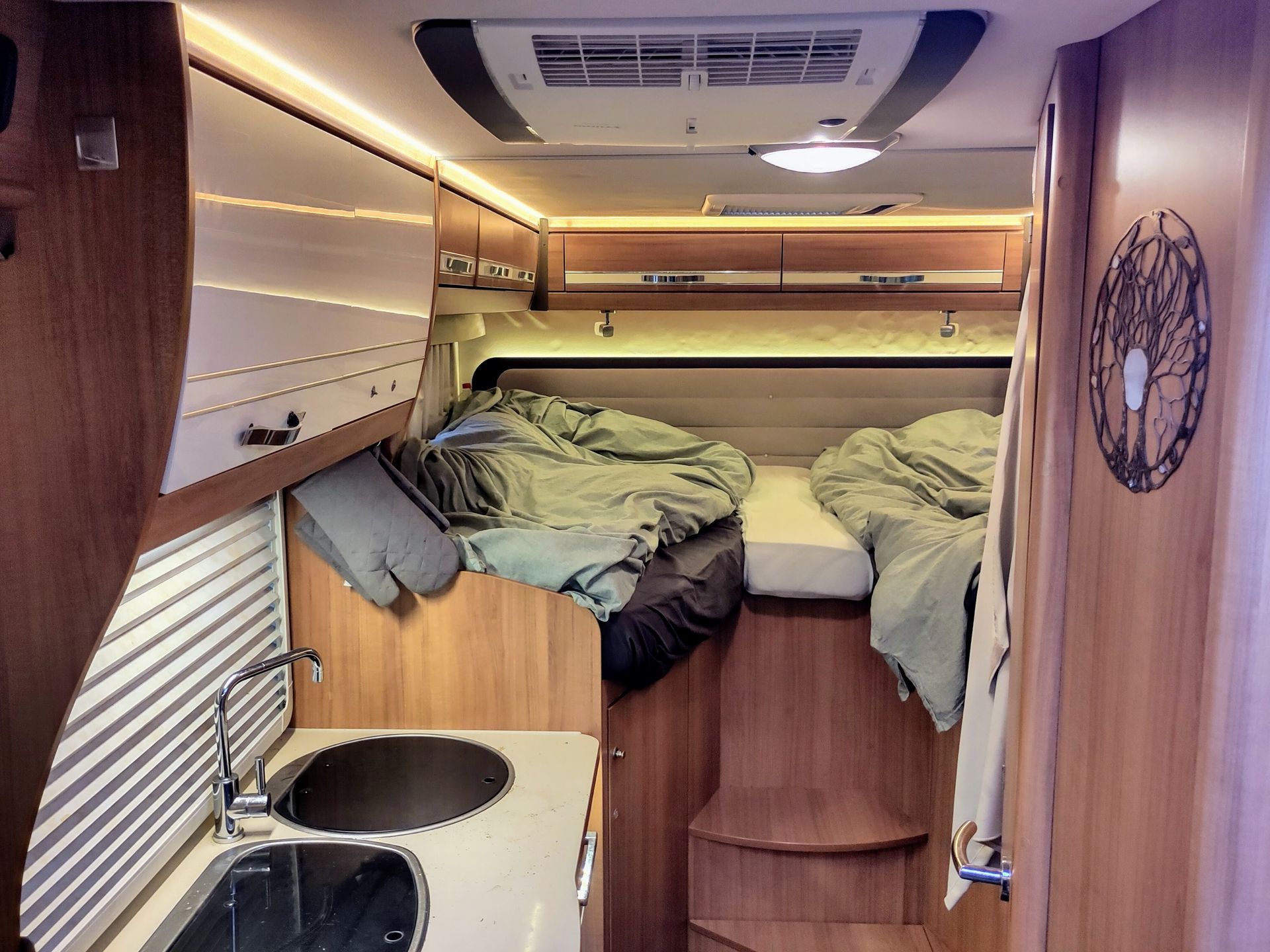De binnenkant van een camper met twee bedden en een wastafel
