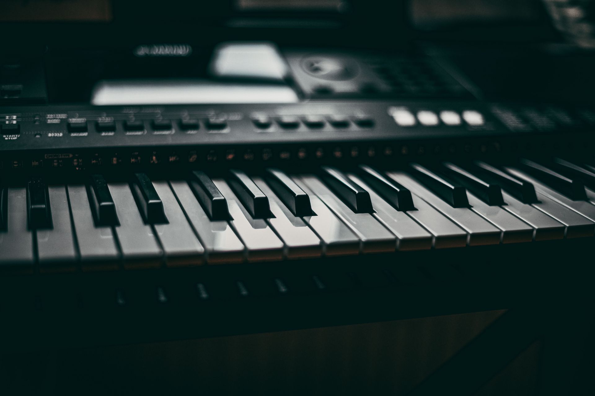 Close-up of an electronic keyboard with black and white keys in dim lighting