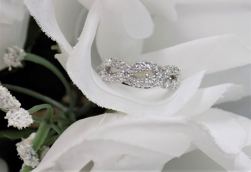 Diamond-studded intertwined ring resting on a white flower