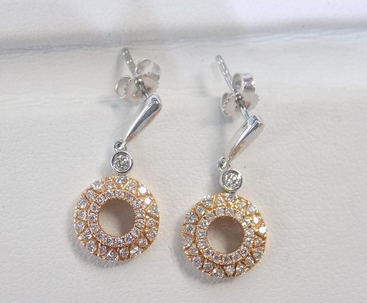 Pair of gold and diamond drop earrings on a white surface.