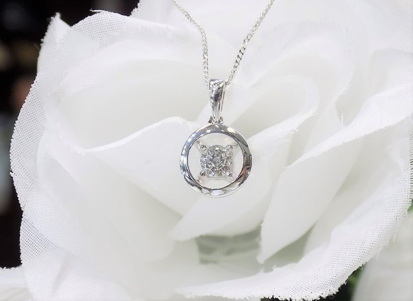 Silver necklace with diamond pendant on a white floral background