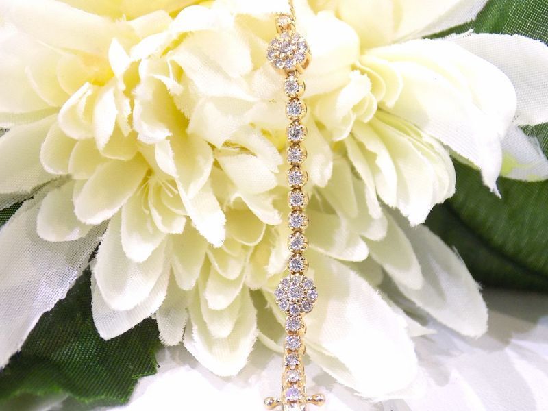 Gold bracelet with diamonds in front of white flowers