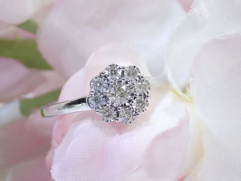 Diamond cluster ring resting on pink and white flower petals