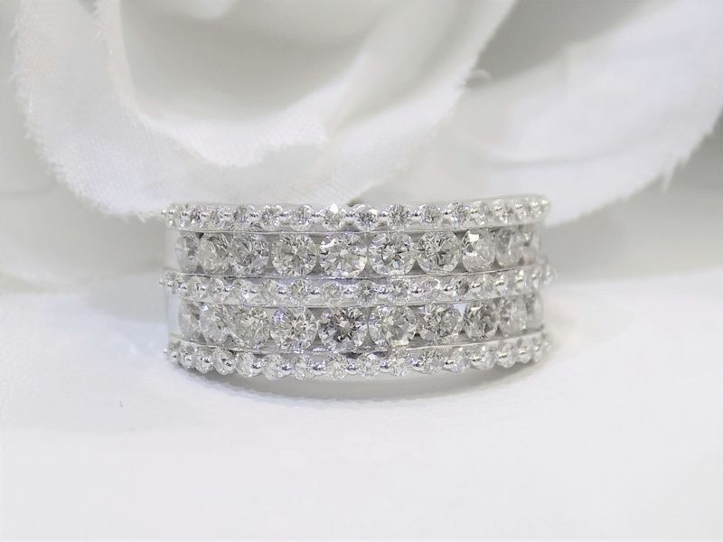 Diamond eternity ring with three rows of round diamonds on a white surface