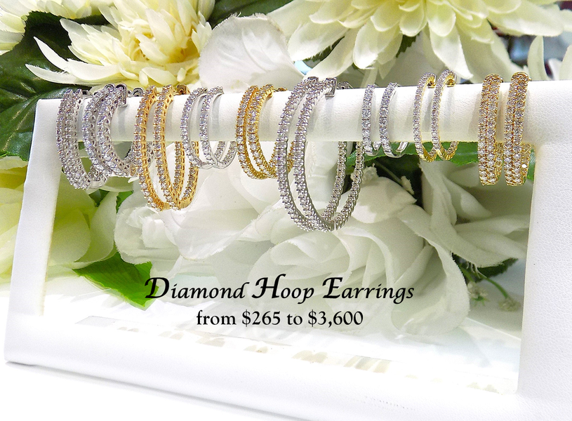 Diamond hoop earrings displayed on a white stand with flowers in the background