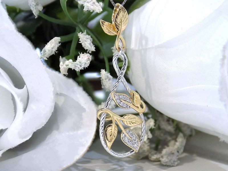 Gold and silver leaf pendant necklace with diamonds on white flower background