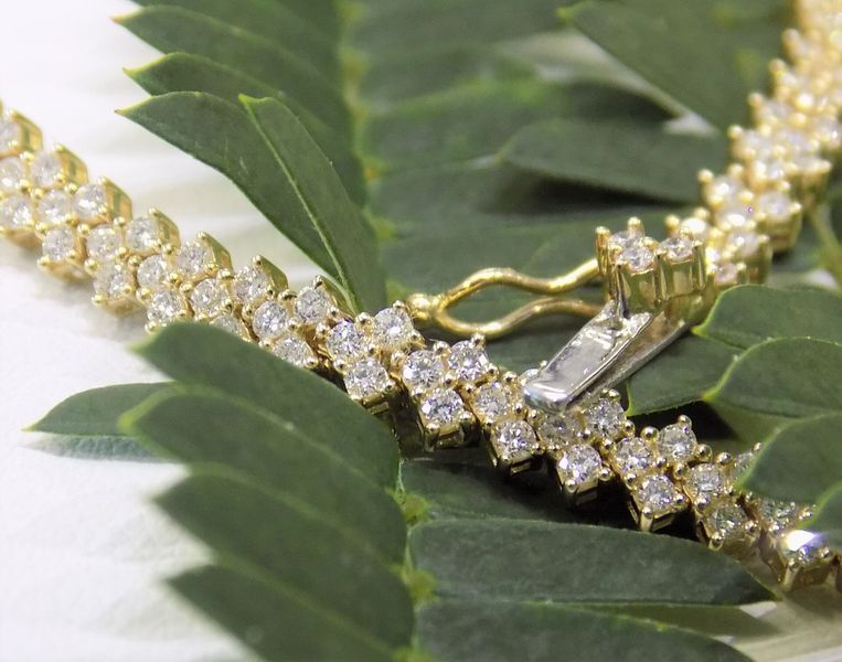 Gold and diamond bracelet on green leaves