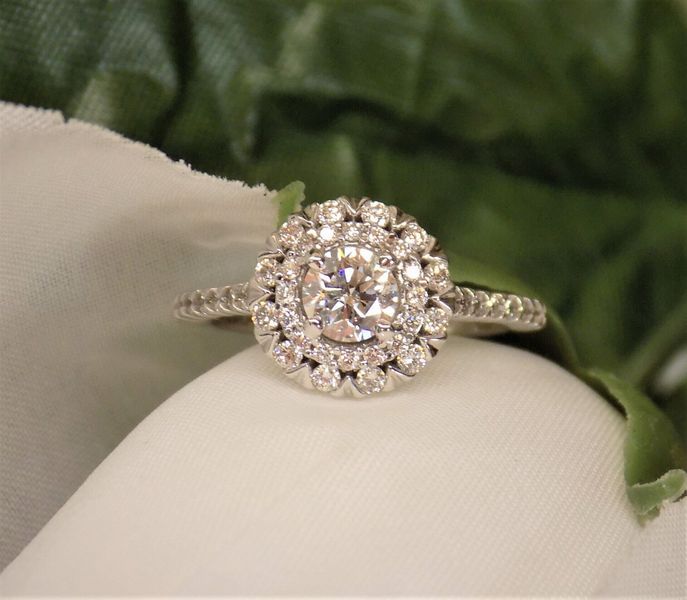 Diamond engagement ring with a double halo on a white surface