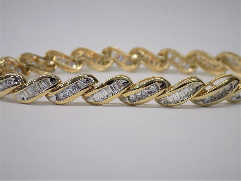 Gold bracelet with baguette diamonds in a wavy design.