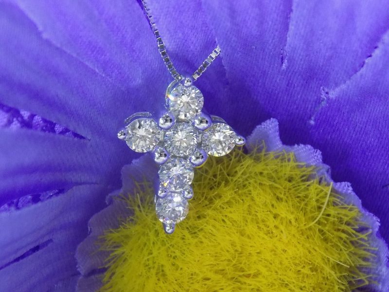 Diamond cross pendant on a blue and yellow flower