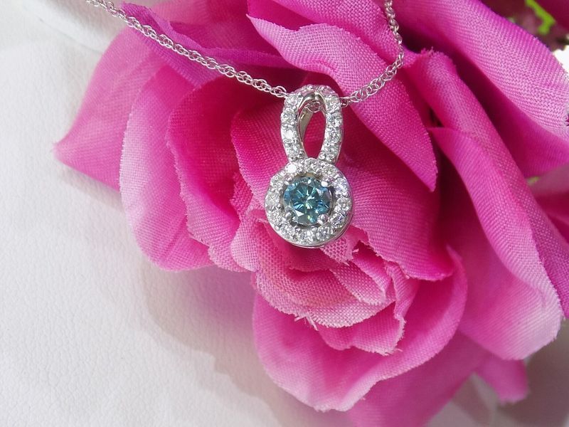 Diamond pendant with blue center stone on pink flowe.