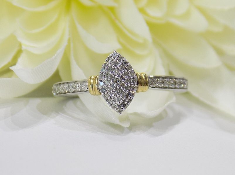 Diamond ring with marquise-shaped cluster, gold accents, and pave band