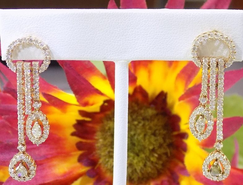 Diamond drop earrings displayed on a stand