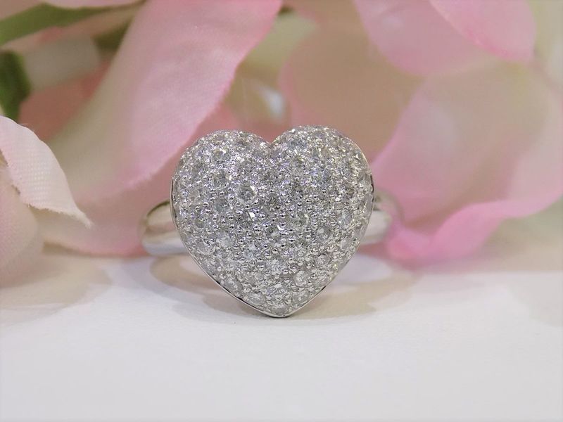 Diamond-studded heart-shaped ring on a white surface