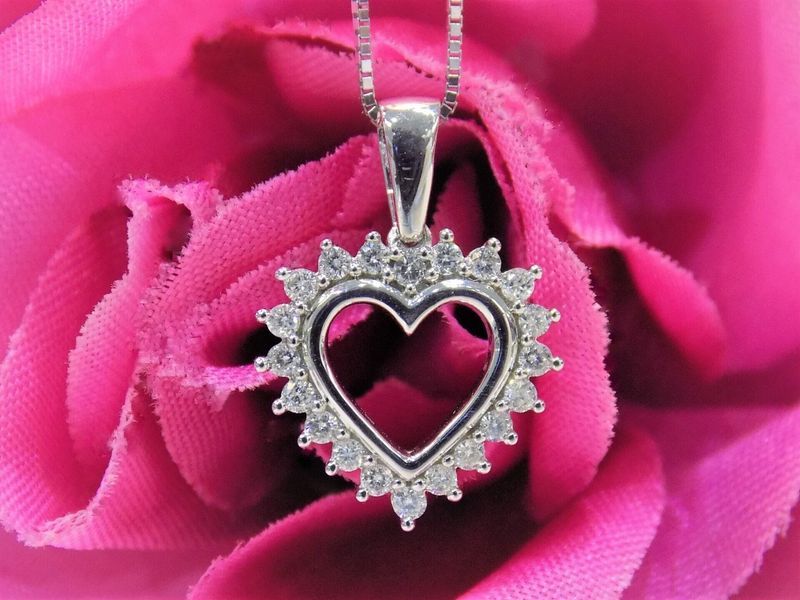 Heart-shaped diamond pendant necklace on a pink rose