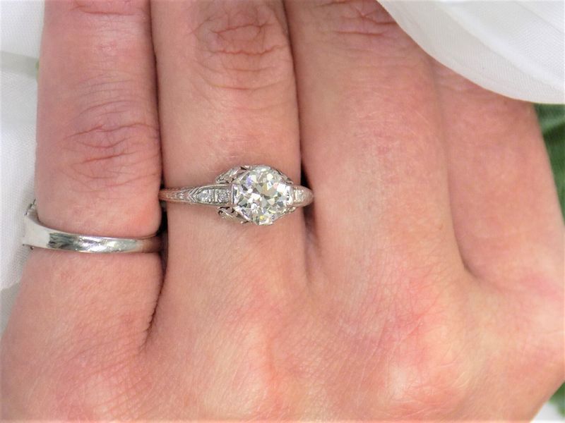 Close-up of hand wearing a diamond engagement ring and a silver band