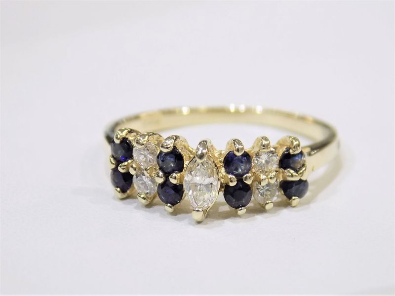 Gold ring with alternating dark blue and clear marquise-cut gemstones