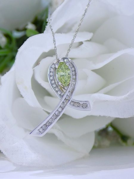 A white gold ribbon pendant with a green gemstone center