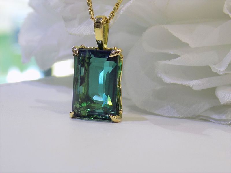 Gold pendant with emerald-cut green gemstone