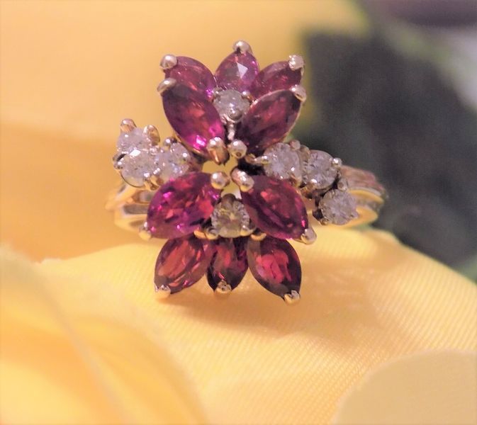 Gold ring with a cluster of red and clear gems in a floral design
