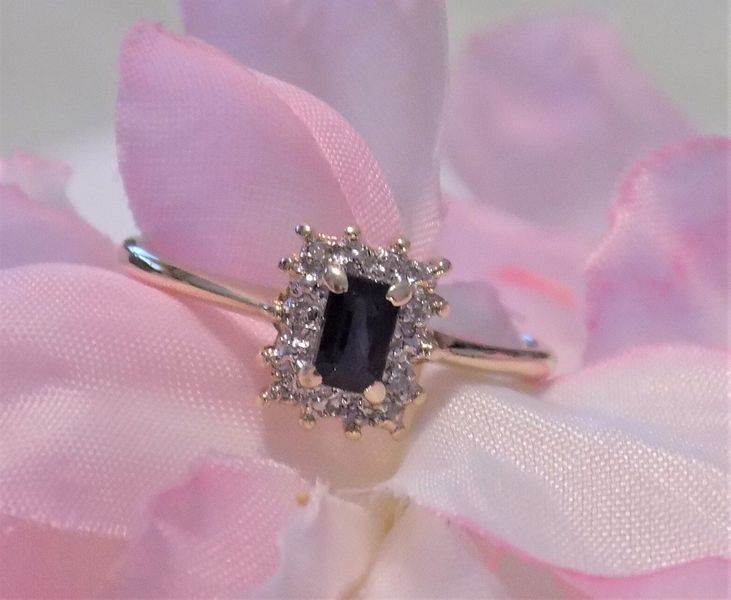 Gold ring with a blue rectangular gemstone and white diamond halo