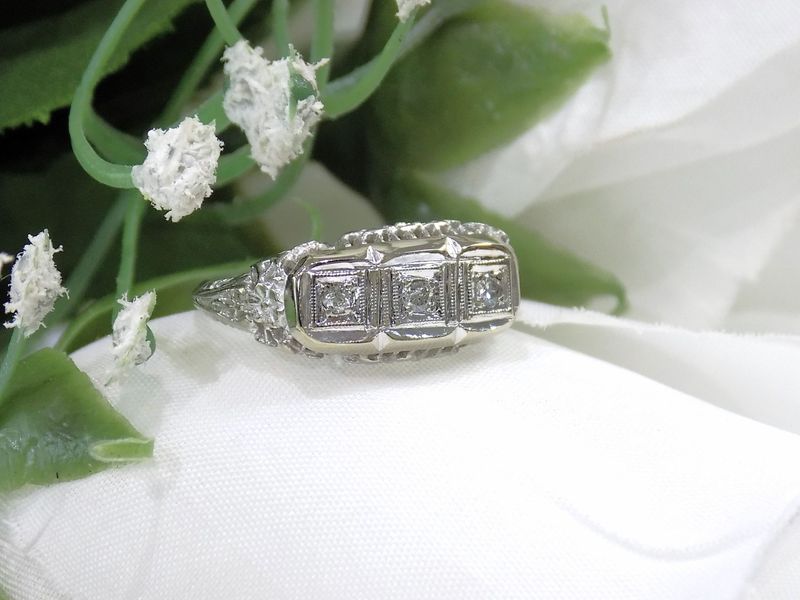 Diamond ring with three square-cut stones on a white flower